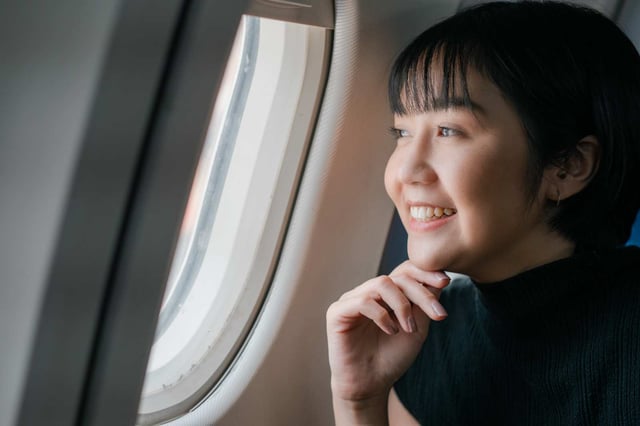 Excited Asian Women Looking Outside Plane Window