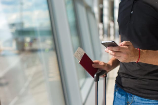 Man Holding Phone Passport Boarding Pass At Airport