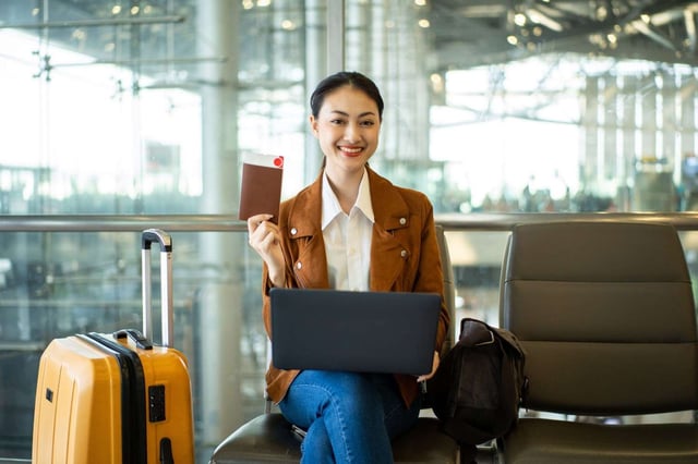 Young Businesswoman Working on Laptop with Passport at Airport Terminal
